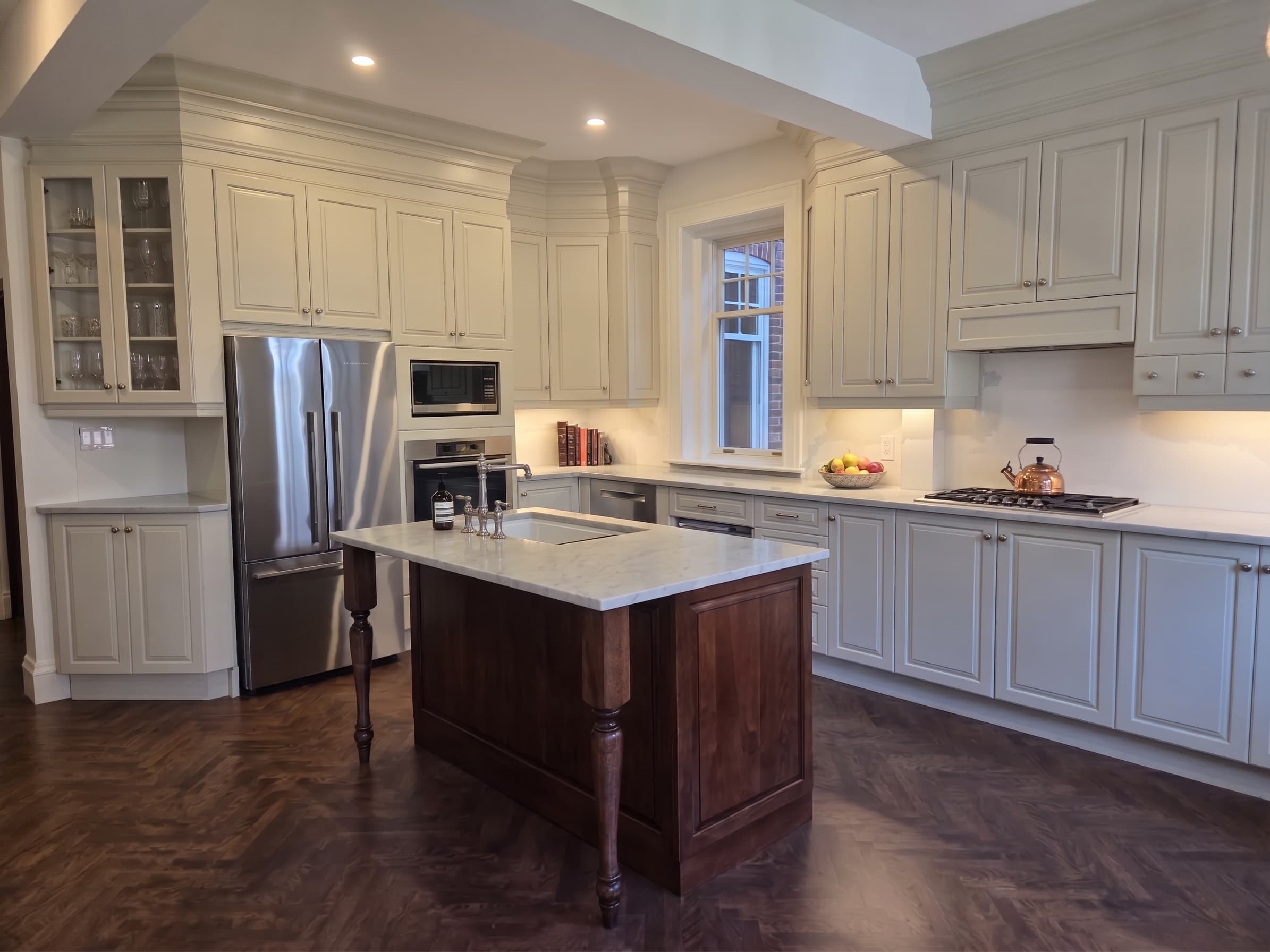 Freshly painted cream kitchen cabinets around a marble-topped island